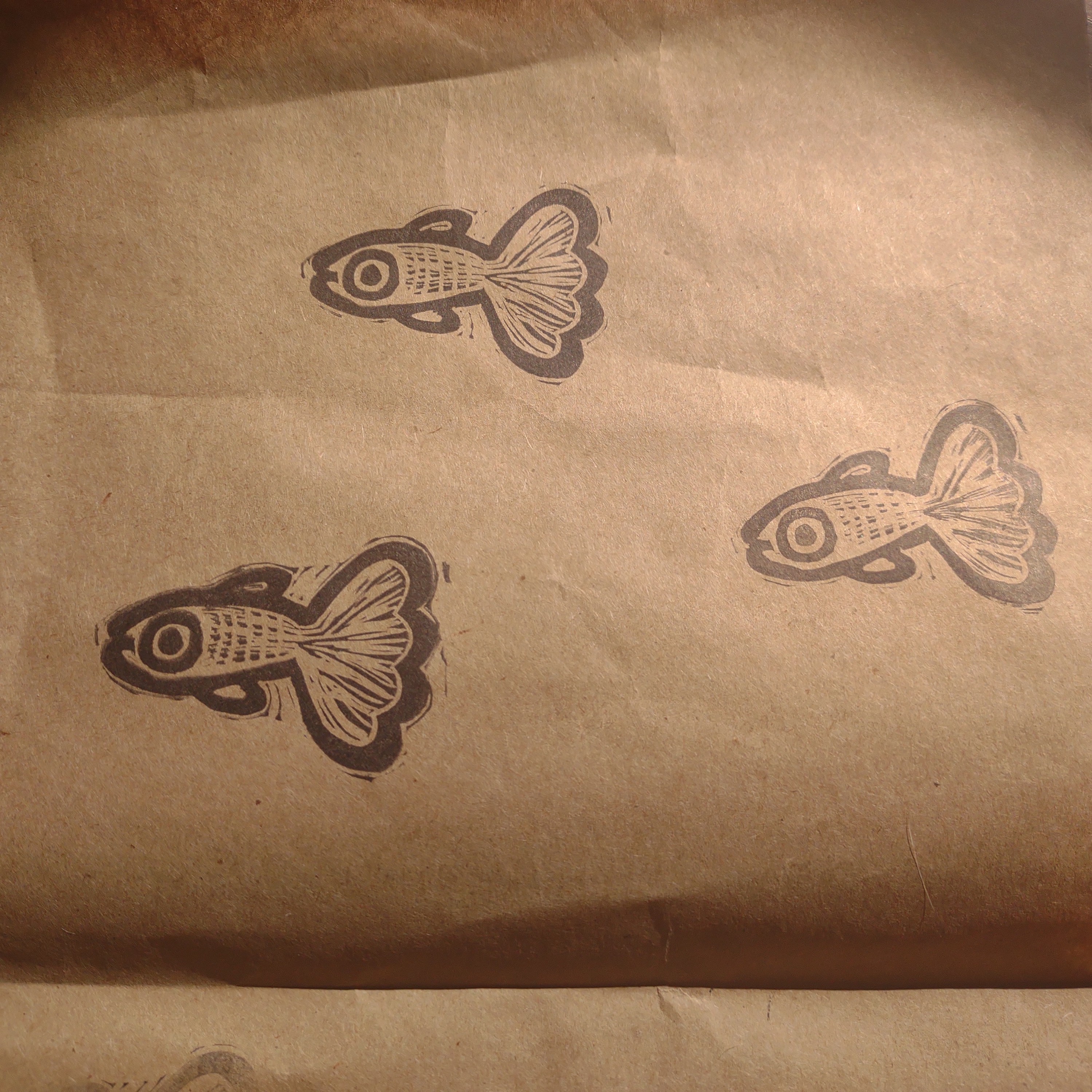 black stamp on brown paper of three big eyed guppies